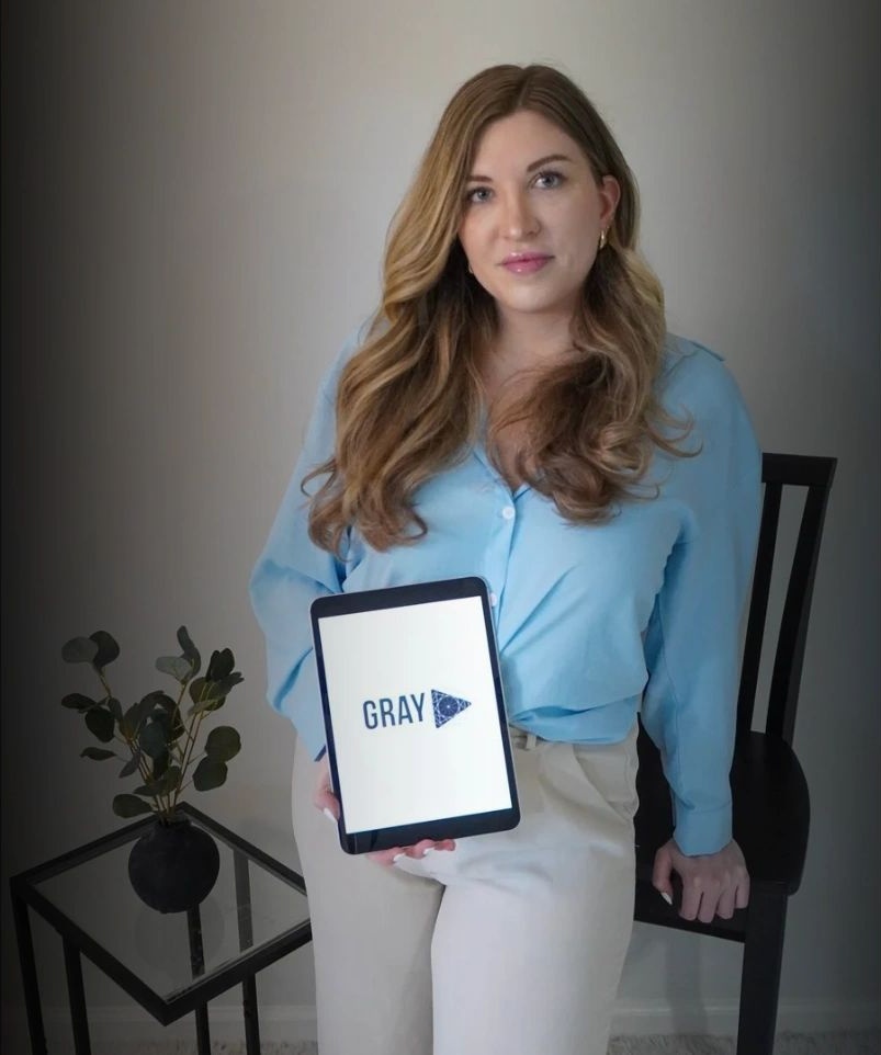 Paige holding a tablet with the Gray Multimedia logo